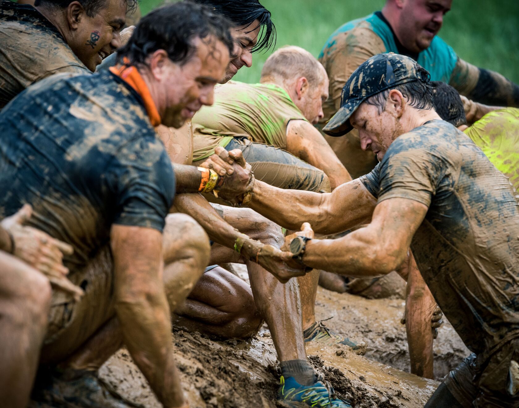 Participants helping their teammates pass through the mud