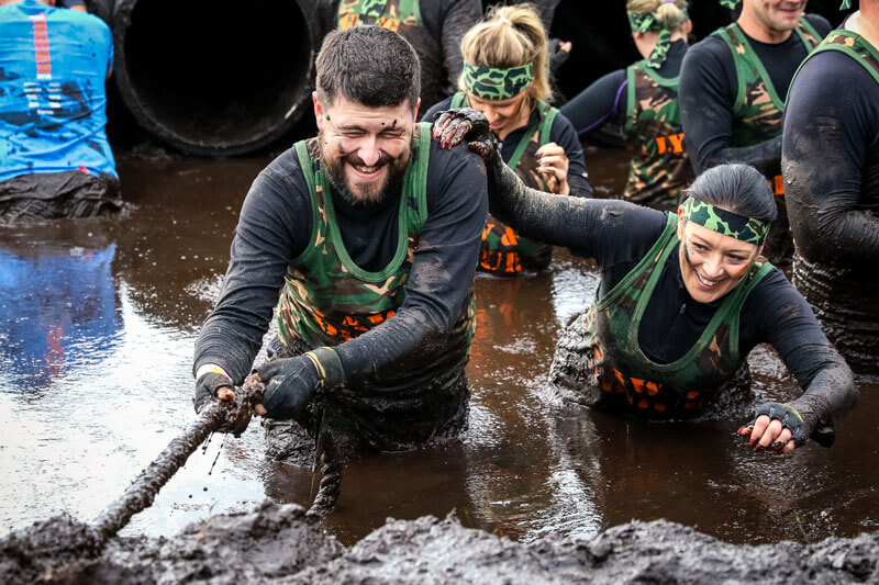 Participant holding tightly on a rope to cross mud waters
